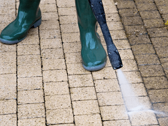 Power washing concrete driveway to eliminate grime, moss, and debris in Bedford area.